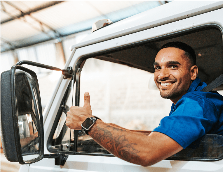 Man smiling, giving thumbs up in truck.