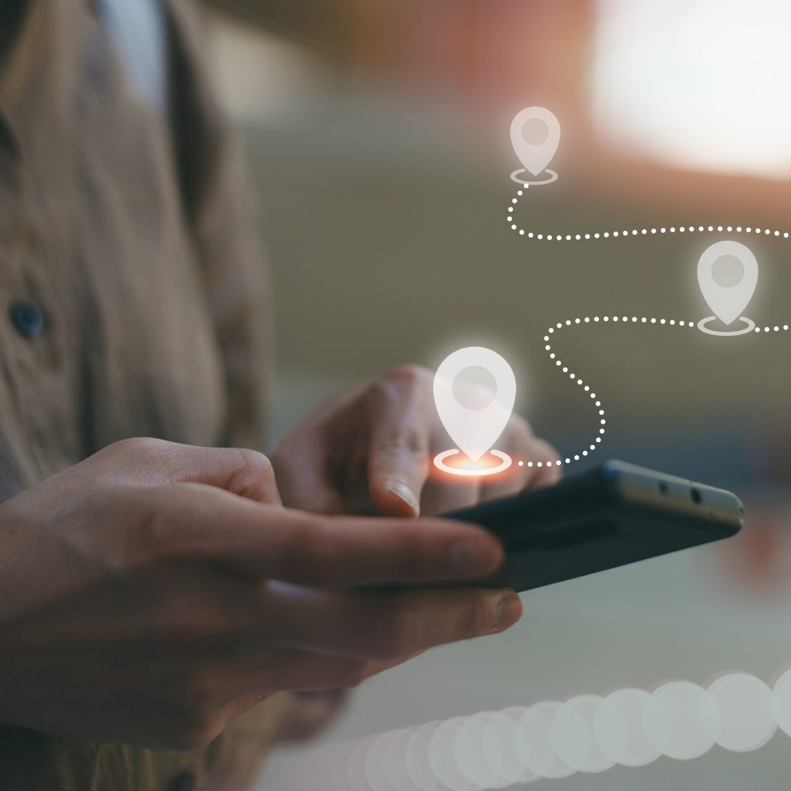 Person using smartphone with location icons.